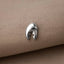 A silver lobster clasp is resting on a beige fabric surface.