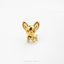 A small, shiny gold-colored dog figurine is sitting on a white surface.