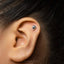 A close-up of a person's ear with a small silver earring in the earlobe.