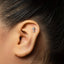 a close-up view of a person's ear with a small silver key-shaped earring inserted into the earlobe.