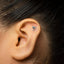 A close-up of a person's ear with a small silver earring in the earlobe.
