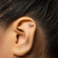 A close-up of a person's ear with a small silver earring in the earlobe.