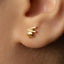 A close-up of a person's ear with a small gold earring in the earlobe.