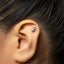 A close-up of a person's ear with a small silver earring in the earlobe.