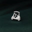 A small silver golf cart pin is placed on a dark green textured surface.