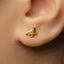 A close-up of a person's ear wearing a gold-colored earring shaped like a megaphone.