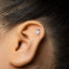 A silver earring with a small leaf-like design is visible in the person's ear.