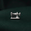 A silver sewing machine charm is placed on a dark green fabric background.