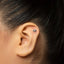 A close-up of a person's ear with a small silver earring in the earlobe.