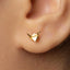 A close-up view of a person's ear adorned with a small gold earring featuring a paper crane design.