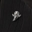 A small silver ghost pin is resting on a dark fabric surface.