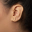 A close-up view of a person's ear adorned with a small gold earring featuring a paper crane design.