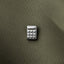 A close-up image of a small metal calculator pin resting on a textured fabric surface.