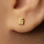 A close-up view of a person's ear with a small gold earring in the earlobe.