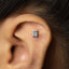 A small silver calculator-shaped earring is visible in the person's ear.