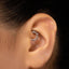 A close-up of a person's ear with a decorative metal ring or earring in the earlobe.