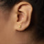 A close-up view of a person's ear with a small gold earring in the earlobe.