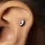 A silver earring with a kidney-shaped design is visible in the image.