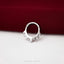 A silver ring with a unique design is placed on a red fabric surface.