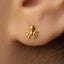 A close-up of a person's ear with a small gold-colored earring featuring an octopus design.