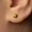 A close-up of a person's ear with a small gold earring in the earlobe.
