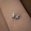 A pair of silver earrings with star-shaped designs is resting on a textured fabric surface.