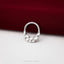 A silver ring with a textured surface sits on a red fabric background.