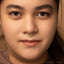 A close-up portrait of a young woman with a nose ring, looking directly at the camera with a neutral expression.