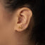 A close-up of a person's ear with a pair of gold earrings attached.