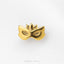 A gold-colored metal mask with a pointed top and two eye holes is shown against a white background.