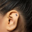 A close-up of a person's ear with a small silver earring in the earlobe.
