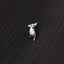 A small silver charm in the shape of a bird is resting on a textured black surface.
