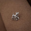A small silver dog figurine is sitting on a textured brown surface.