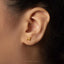 A close-up of a person's ear wearing a small gold-colored earring with a small animal design.
