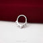 A silver ring with a unique design is placed on a red fabric surface.