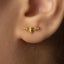 a close-up view of a person's ear with a small gold earring featuring a bat design.