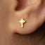 A close-up of a person's ear with a small gold cross-shaped earring in the earlobe.