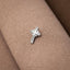 A silver cross pin is resting on a textured fabric surface.