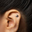 A close-up of a person's ear with a small silver earring in the earlobe.