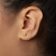 A close-up of a person's ear with a small gold earring in the earlobe.