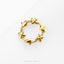 A gold-colored ring with a circular design featuring small star-shaped or flower-shaped elements.