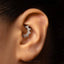 A close-up of a person's ear with a decorative piercing, specifically an earring with a floral design.