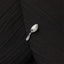 A close-up image of a silver spoon with a decorative handle, resting on a black fabric surface.