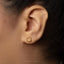 A close-up view of a person's ear adorned with a small gold earring featuring a circular design.