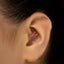 A close-up of a person's ear with a heart-shaped earring in the earlobe.