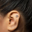 A close-up of a person's ear with a small silver earring in the earlobe.
