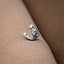 A silver-colored metal object, resembling a small, ornate piece, is resting on a textured fabric surface.