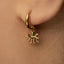 A close-up view of a person's ear wearing a gold-colored earring with an octopus charm hanging from it.