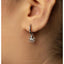 A close-up view of a person's ear with a silver earring featuring an octopus charm hanging from it.