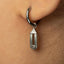 A close-up view of a person's ear adorned with a silver hoop earring featuring a small pendant.